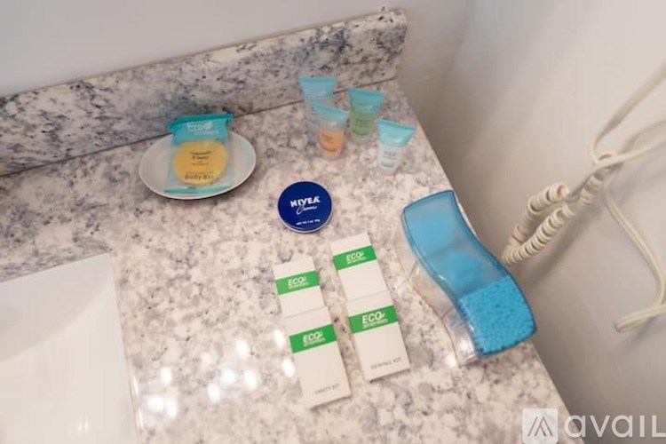 A bathroom counter with a bottle of shampoo, a hairbrush, and three small containers of hair products.