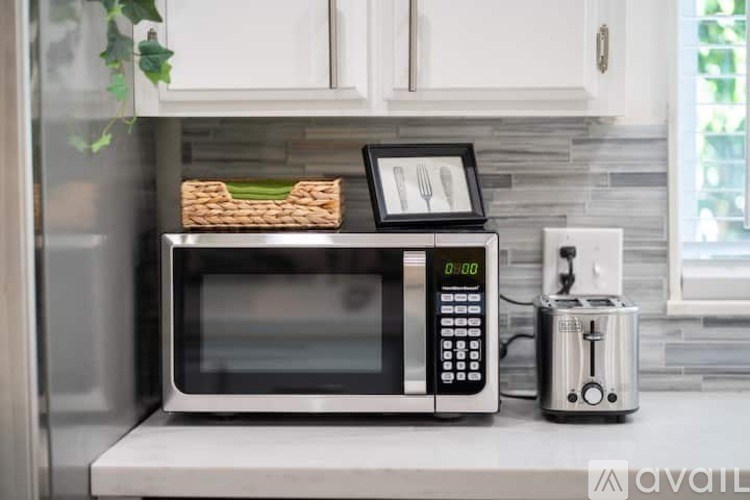 A black microwave with a digital clock and a basket of bread on top of it.