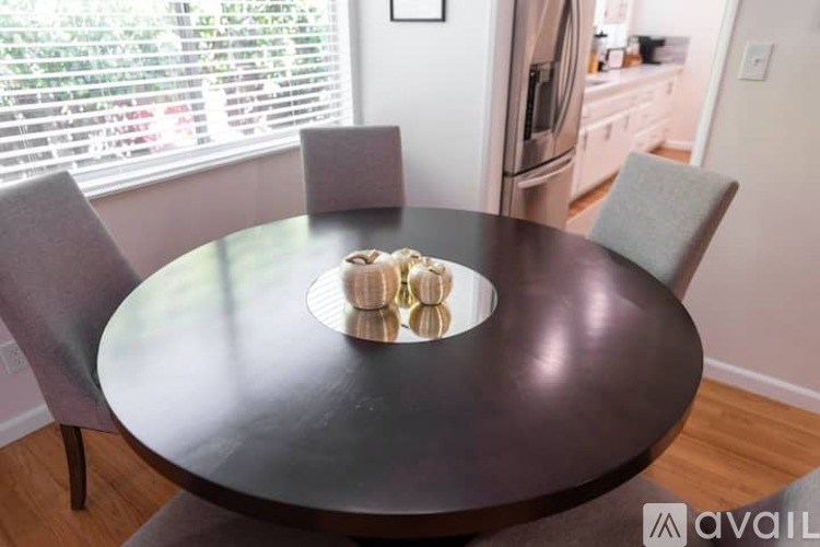 A modern dining table with chairs and a bowl of fruit on top.