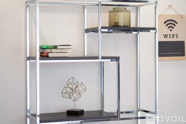 A shelf with books, a lamp, and a geometric sculpture.