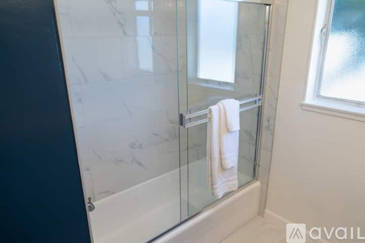 A white towel is hanging on a glass shower door.