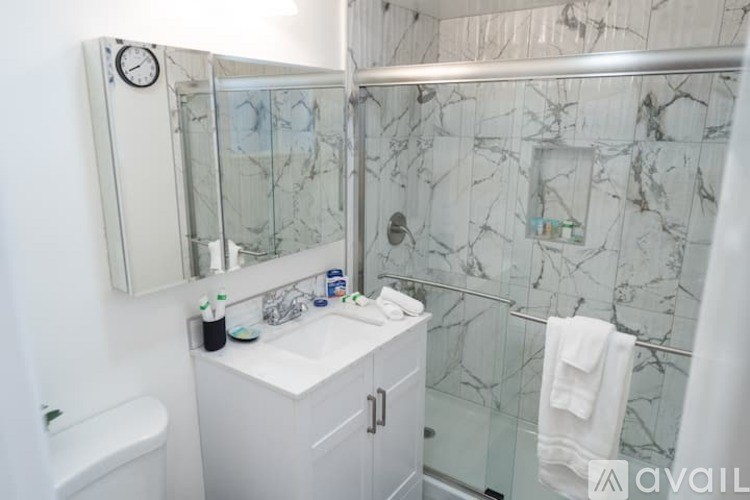 A bathroom with a marble wall and a white cabinet.