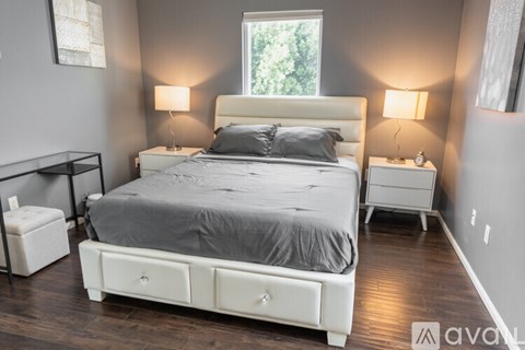 A bedroom with a large bed and two lamps.