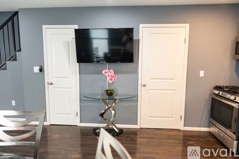 A kitchen with a glass table and a TV mounted on the wall.