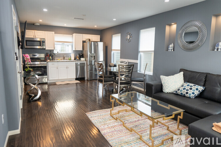 A modern kitchen with a black couch and a glass coffee table.