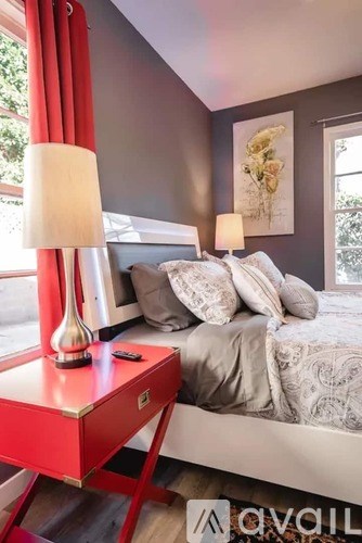 A bedroom with a bed, a red table, and a lamp.