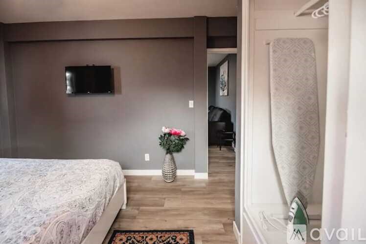 A bedroom with a bed, a vase with flowers, and a television on the wall.