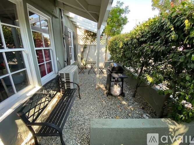 A black bench sits on a patio next to a table and a fire pit.