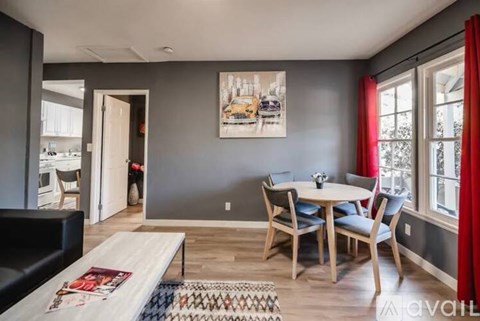 A dining room with a table set for four and a couch.