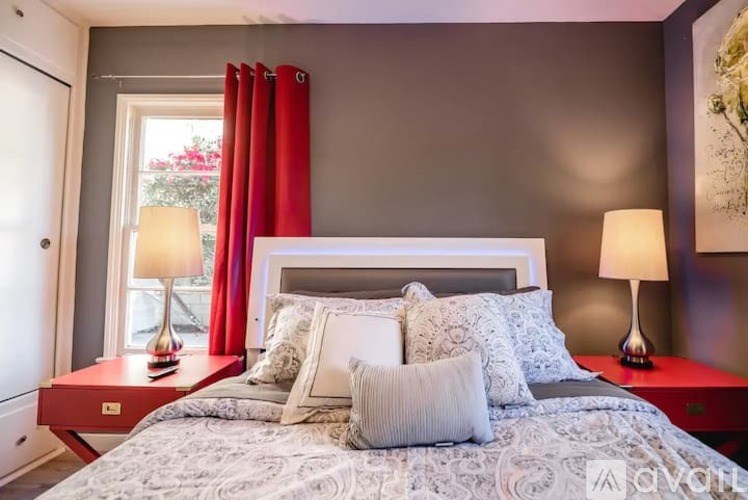 A bedroom with a large bed, red lamps, and a red headboard.