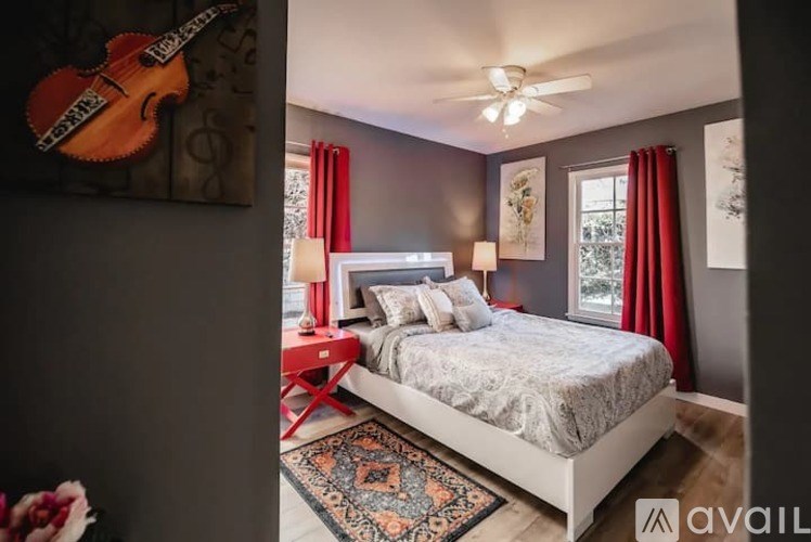 A bedroom with a bed, a guitar, and a ceiling fan.