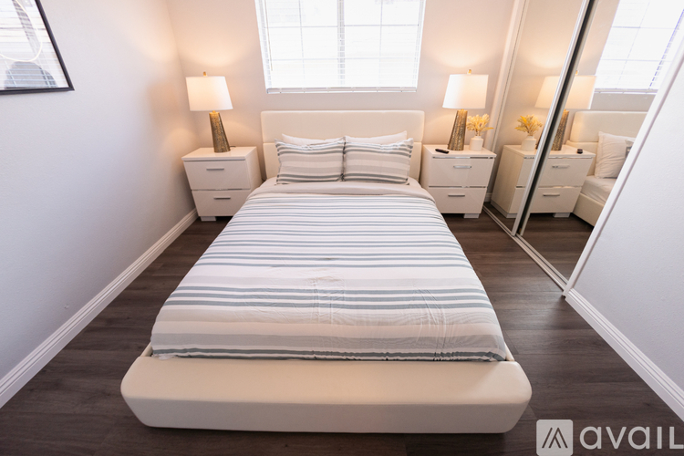 A bedroom with a large bed and two nightstands with lamps.