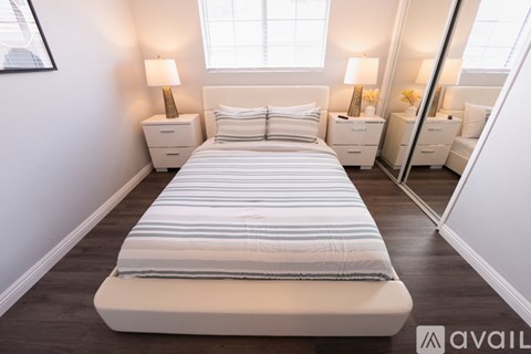 A bedroom with a large bed and two nightstands with lamps.