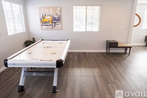 A pool table in a room with a painting on the wall and a bench.