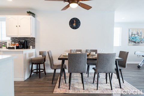 A dining room with a table set for six and a fan on the ceiling.
