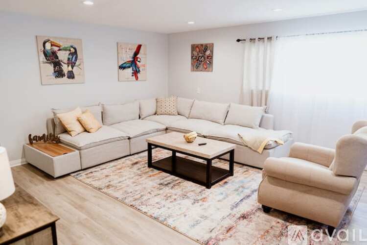 A living room with a white sofa, a coffee table, and two chairs.
