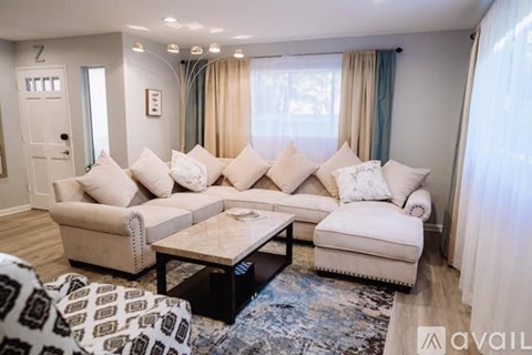 A living room with a white sofa set and a patterned rug.