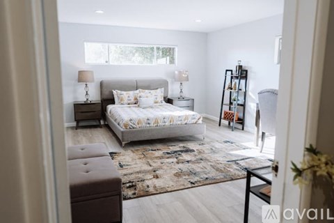 A bedroom with a large bed and a rug on the floor.