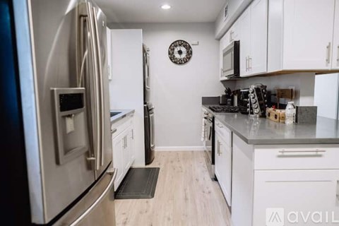 A kitchen with a stainless steel refrigerator and white cabinets.