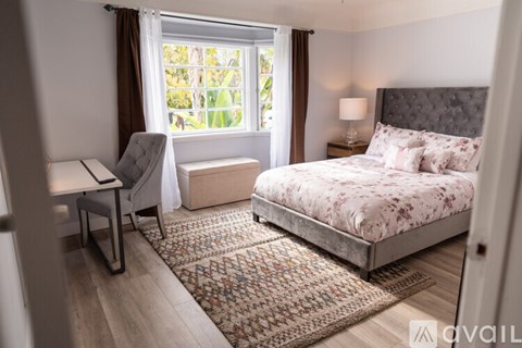 A bedroom with a bed, chair, and window.