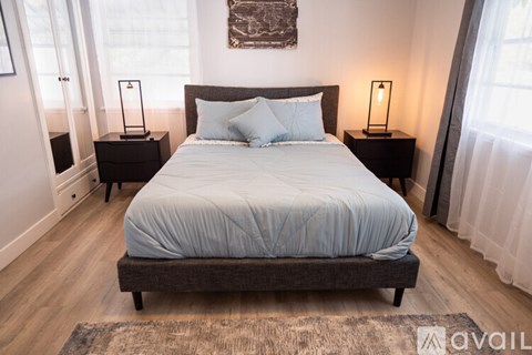 A bedroom with a large bed and two nightstands with lamps.