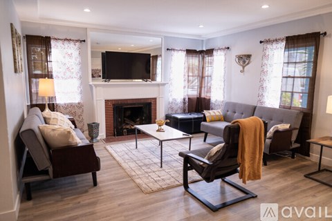 A living room with a fireplace and a television mounted above it.