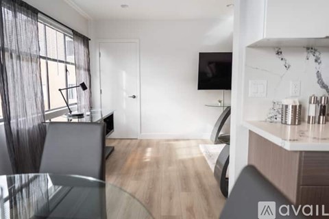 A modern living room with a glass table and a television on the wall.