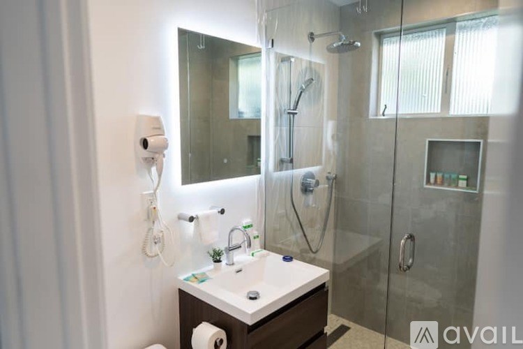 A bathroom with a mirror, sink, and shower.