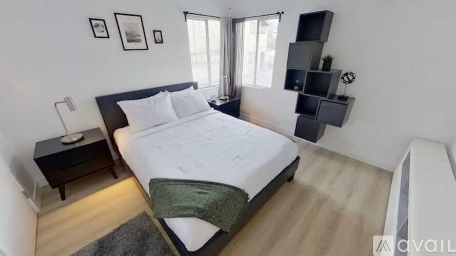 A bedroom with a large bed, a nightstand, and a wall-mounted shelf.