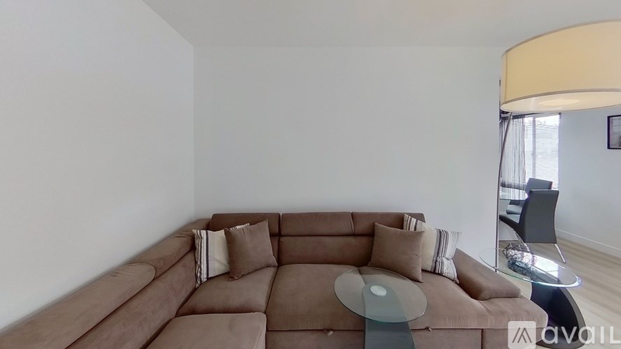 A living room with a brown sofa and a glass coffee table.
