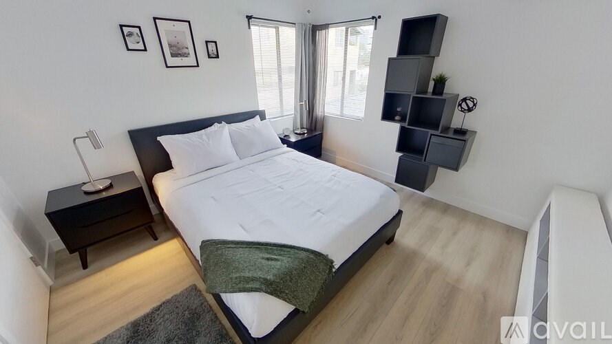 A bedroom with a large bed, a nightstand, and a wall-mounted shelf.