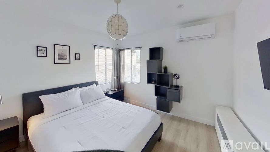 A bedroom with a large bed and a window with curtains.