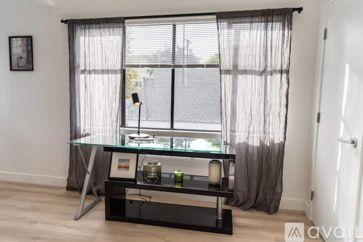 A glass table with candles on it in front of a window with curtains.