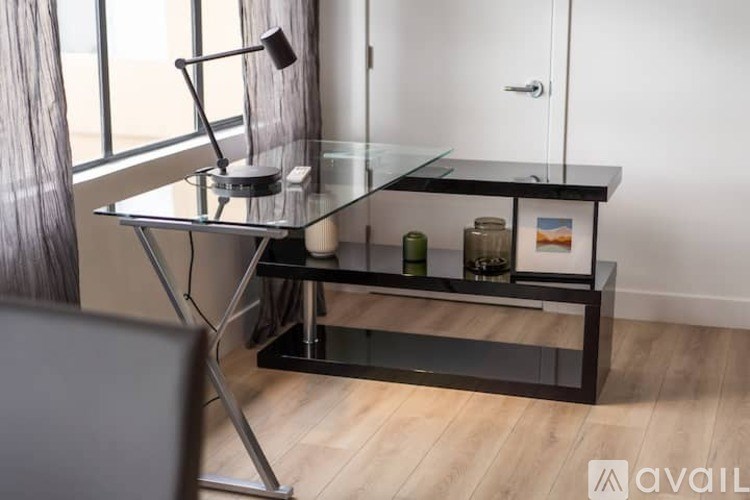 A glass desk with a metal frame and a lamp on it.