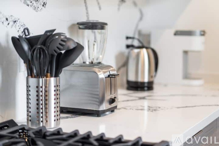 A kitchen counter with a blender, toaster, and a set of utensils in a holder.