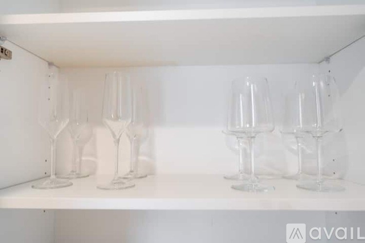 Four wine glasses are lined up on a shelf.
