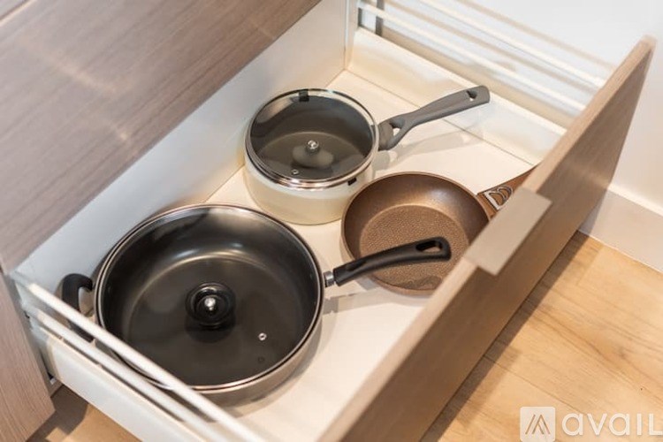 A drawer with three pots and pans in it.