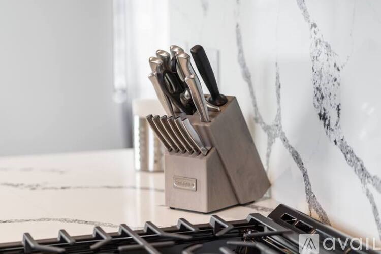 A set of knives is stored in a holder on a marble countertop.