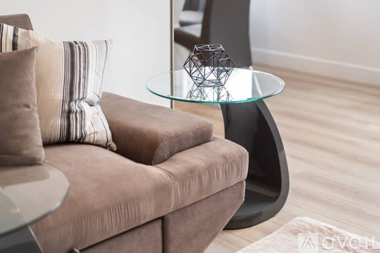 A modern living room with a brown sofa and a glass table.