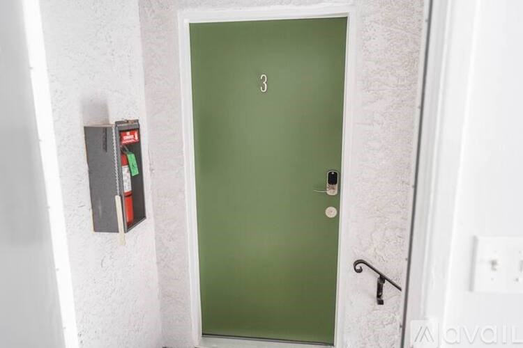 A green door with a black handle and a mailbox on the wall.