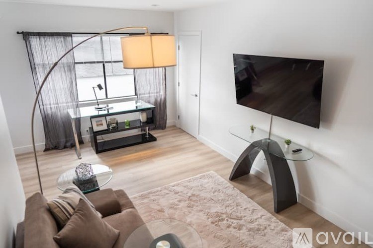 A modern living room with a large TV and a glass coffee table.