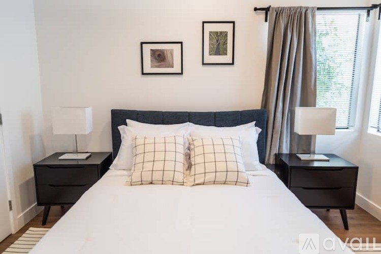 A bedroom with a large bed, two nightstands, and two framed pictures on the wall.