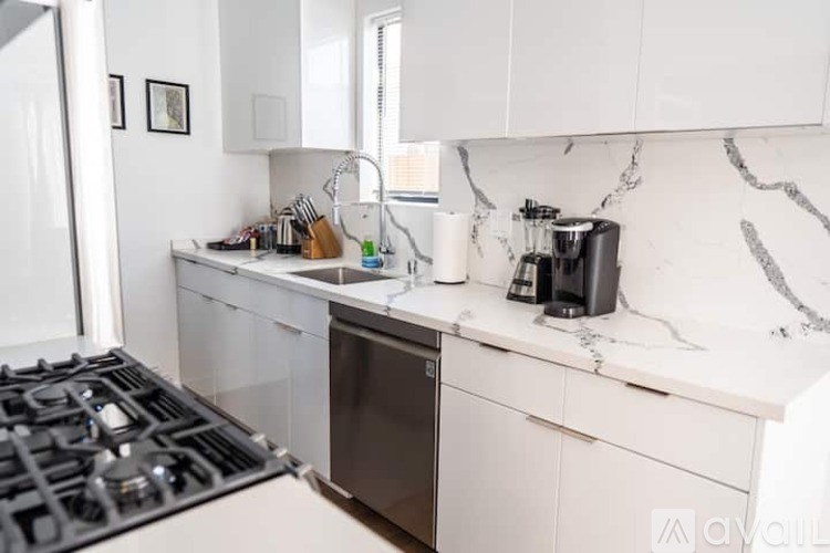 A kitchen with white cabinets and a black stove top.