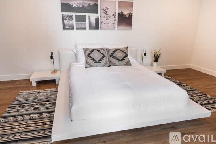 A white bed with a white headboard and two grey and white pillows.