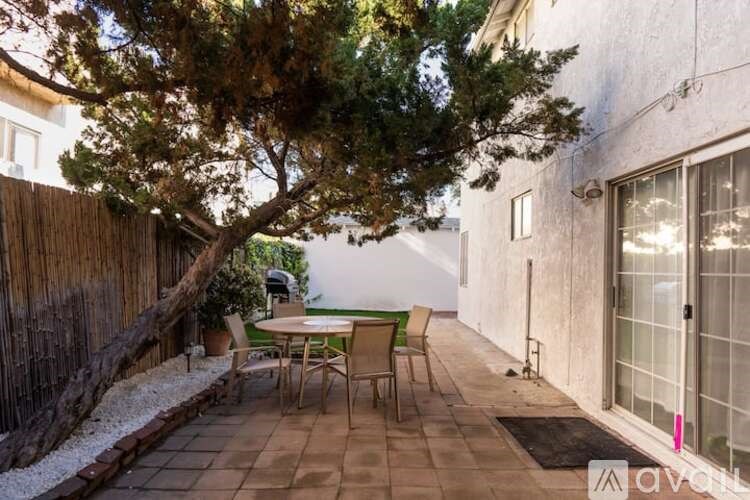 A patio with a table and chairs under a tree.