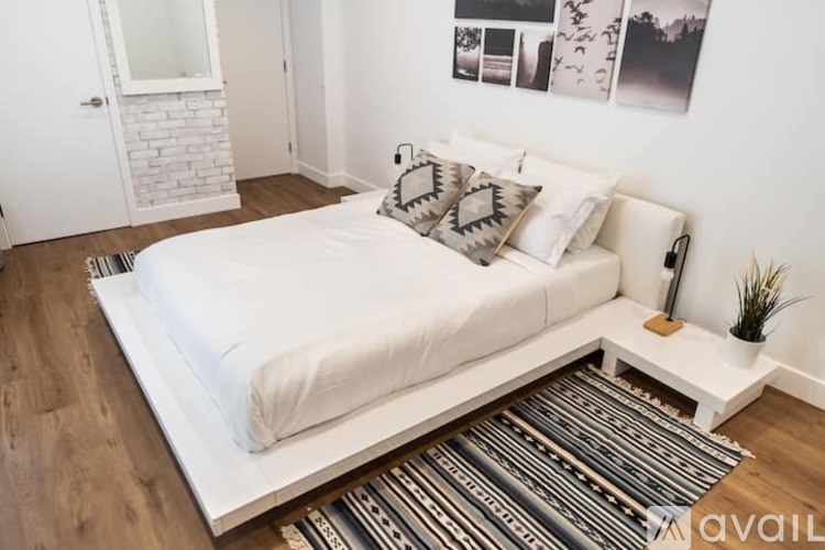 A white bed with a white headboard and a white pillow with a grey pillow case on it.