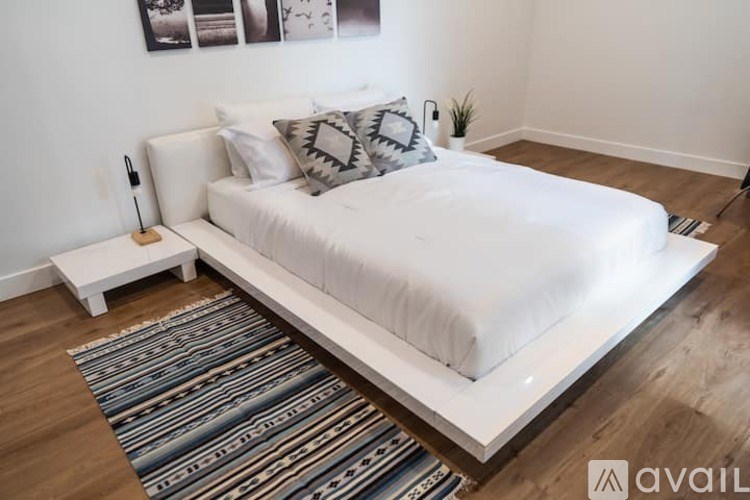 A white bed with a white headboard and a white pillow with a grey and white pillow case.