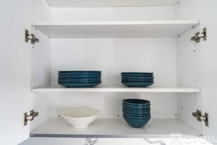 A white cabinet with three shelves holding blue and white dishes.