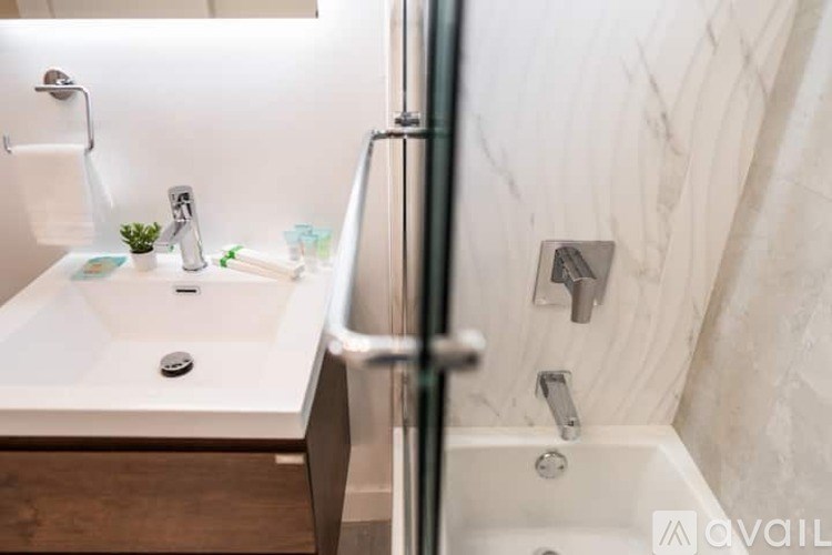 A white sink in a bathroom with a glass shower door.