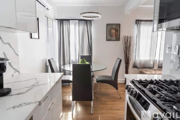 A modern kitchen with a black chair and a white countertop.